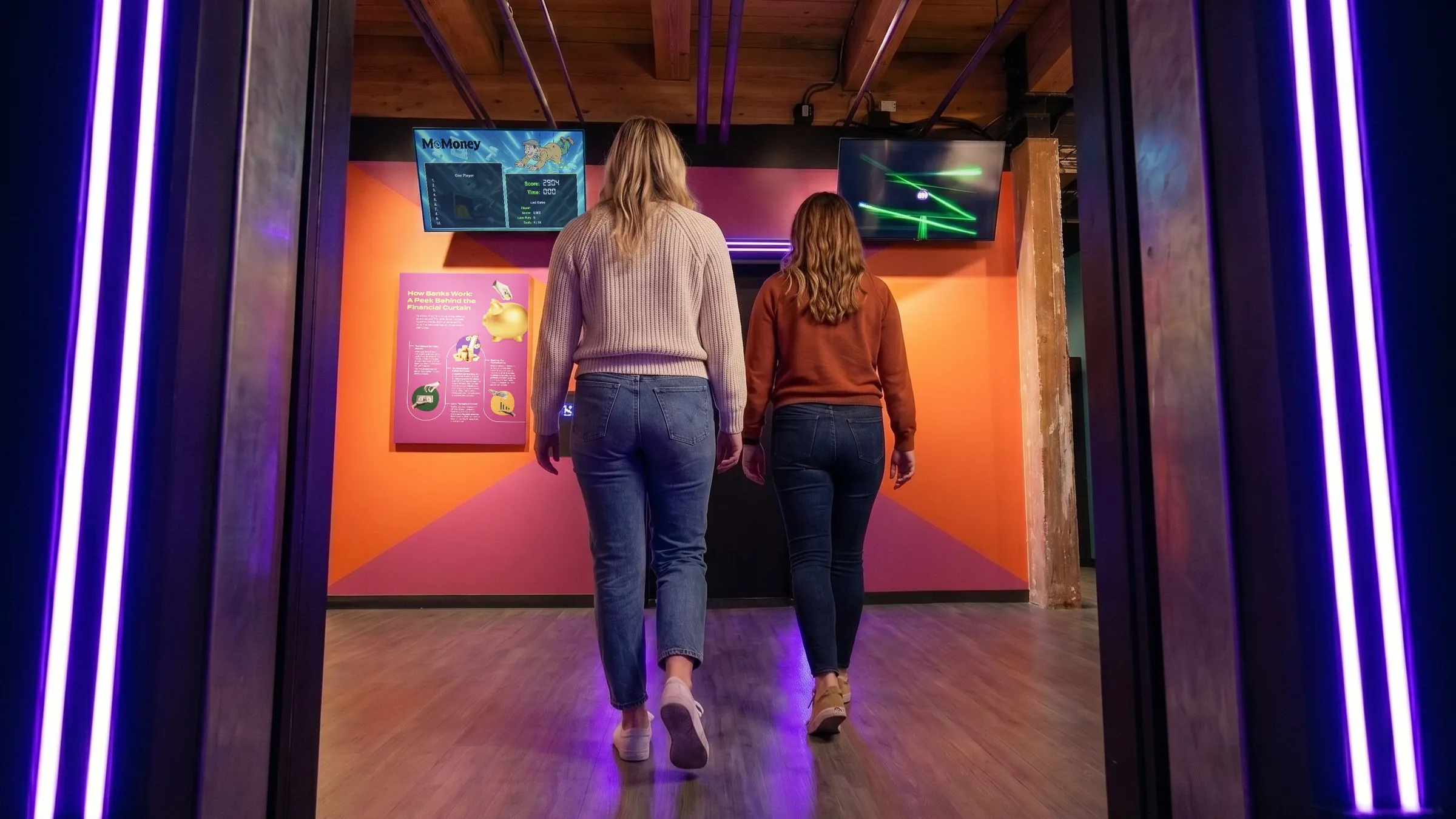 Two visitors entering MoFun's heist exhibit, one of 28 interactive money experiences groups can explore together.